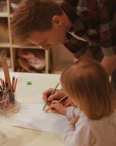 nursery in Bearsden teacher helping girl write